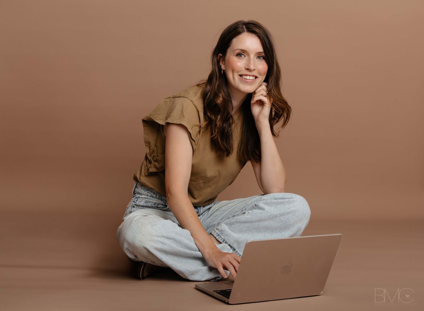 Jess Coleman sitting cross-legged with her laptop
